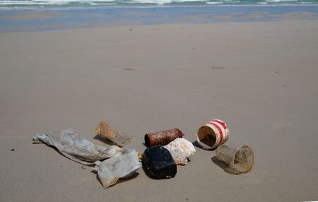 Garbage and chemical cans are collected and put together at a sandy beach.