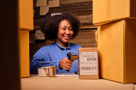 African American female worker in safety uniform using bar code scanner to check shipment orders at parcels warehouse, paper manufacture factory for the packing industry, logistic transport service.の写真素材
