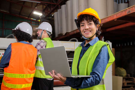 Portrait of safety uniform female engineer worker and hard hat with laptop looks at camera, happy...