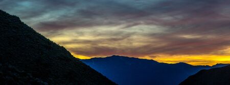 Colors in the sky after sunset behind silhouetted mountains.の写真素材