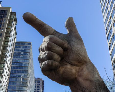 A giant thumb reaching skywards an urban oddity playful yet thought provoking against the cityscapeの素材