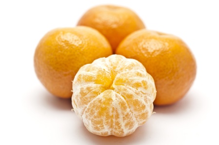Ripe tangerine brushed against not peeled tangerinesの写真素材