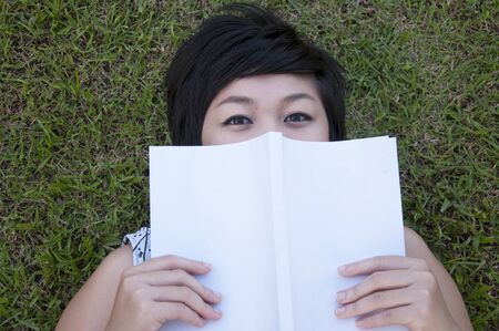 Young woman reading a book in the field
