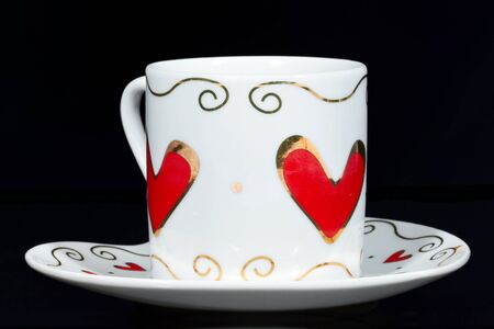 White cup with hearts isolated on black background.の写真素材