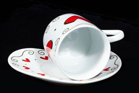 White cup with hearts isolated on black background.の写真素材