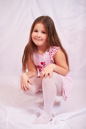 Little girl sitting on her haunches.の写真素材