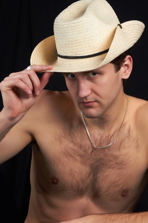 A man sitting in a hat, bare-chested, looks sexy and attractive の写真素材