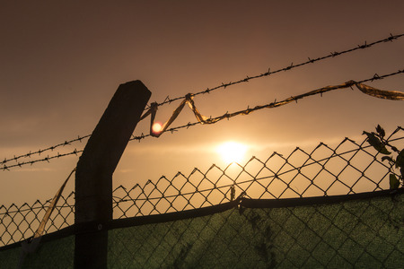 wire silhouette with sky and sun at duskの写真素材