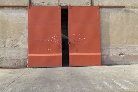 Empty entrance of old hangar with orange doorの写真素材