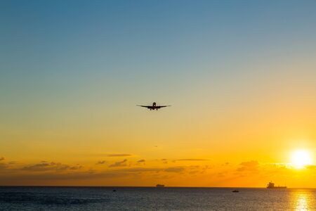 An airplane approaching the runway for landing during the sunsetの写真素材