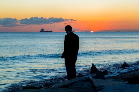 Lonely Single man standing to the sea and sunの写真素材