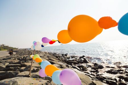 Colorful Baloon on the string near the sea with reverse light, empty imageの写真素材