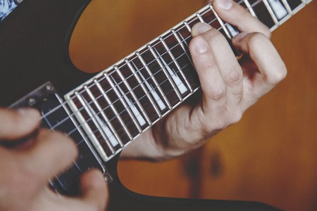 man playing electric guitar close up view, very shallow depth of field image, cinematic effect appliedの写真素材