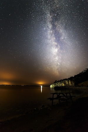 Milky way near the sea, city lights adds sunset effectの写真素材