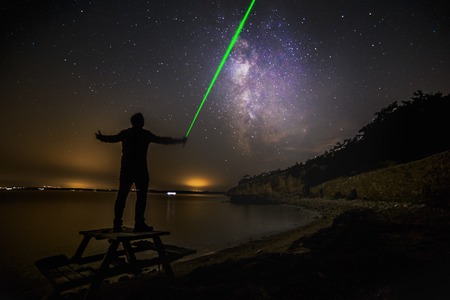 Single man with his laser pointer like lightsaber and milkyway