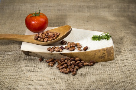 Organic red dried beans over wooden tray and sackcloth, studio image