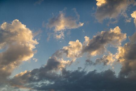 Empty cloudy sky from orange to blue with sun rays during the sunset