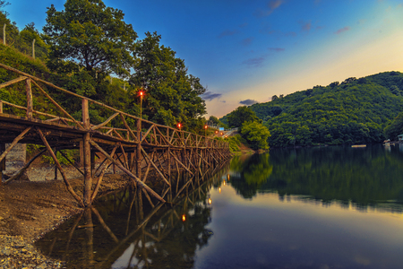 Enlighted empty pier by the lake which is surrended with mountainの写真素材