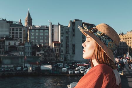 Beautiful girl with orange colored dress posing on the Galata Bridge with Galata Towerの写真素材