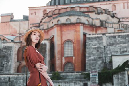Beautiful girl with orange colored dress posing with Hagia Sophia during sunset from Istanbulの写真素材