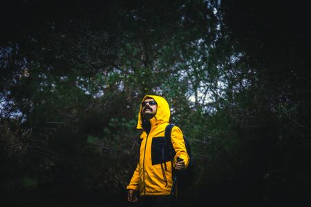 A young man adventurer with contrast yellow jacket posing in a jungle with mystery lightingの写真素材