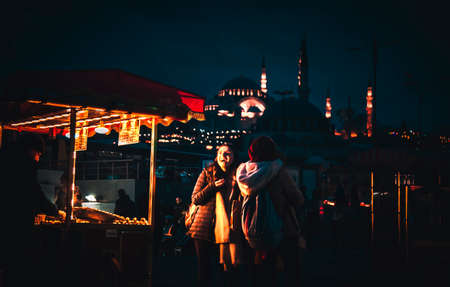 Istanbul, Turkey: March 02, 2020: Two girl buying foods from a vendor in Eminonu Square during...