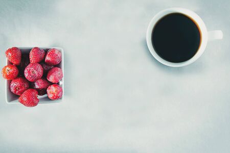Flatlay top view a bowl of fresh strawberry, a cup of coffee on modern concrete background with trend color, copy space includesの写真素材