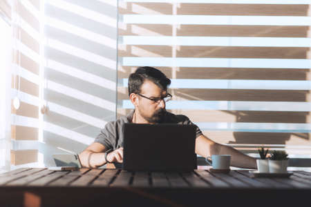 Turkish man working from home with laptop at early morning. Modern illuminated reverse light photo.の写真素材