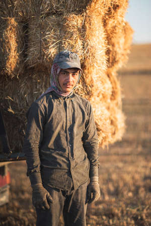 Ankara, Turkey: July 14, 2020: A portrait of an agricultural laborer,he is very young and stacking bales of straw after harvest.のeditorial素材