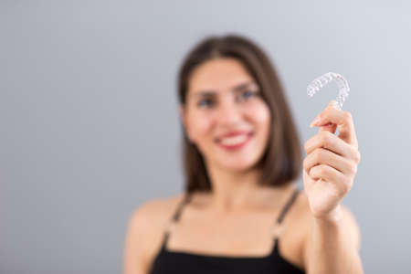 Beautiful smiling Turkish woman is holding an invisalign bracer, Isolated studio shot with copy...