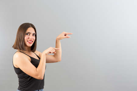 Beautiful Turkish woman with casual clothes is pointing the right side, isolated studio shot with...