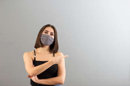 Beautiful Turkish woman portrait in positive mood. She is wearing a protecive mask for new normal concept and gesturing thumbs up.の写真素材