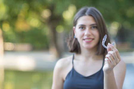 Beautiful smiling Turkish woman is holding an invisalign bracerの写真素材