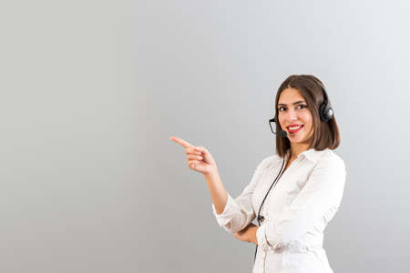 Beautiful Turkish woman with head phone in a studio, isolated shot with copy space, she is pointing...