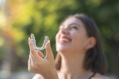 Beautiful smiling Turkish woman is holding an invisalign bracer