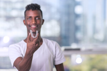 Handsome African Young Man Is Holding An Invisaligner, image with copyspaceの写真素材