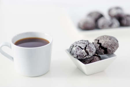 Minimal designed scene, a coffee cup and dark chocolate cookie over plain white background, includes...