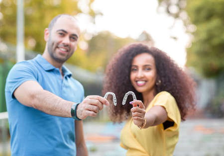 Handsome man with warm smiling is holding an invisaligner. Includes copy and text space.