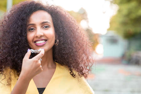 Beautiful smiling African black woman is holding invisaligner. Includes copy and text space.