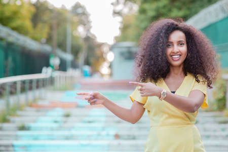 Happy and cheerful Afro Black woman is pointing an empty copy space with her hand, tips and advice conceptの写真素材