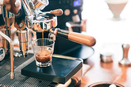 Espresso is being filling to a glass from a portafilter espresso machine. Precision balance equipment is used.の写真素材