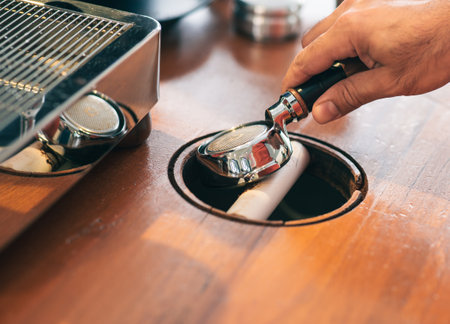 Barista is cleaning coffee portafilter after an espresso session. Closeup detail view from a professional barista desk.の写真素材