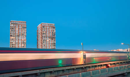 Long Exposure metro train light trails among the apartments during twilight.