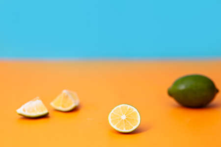 Flat lay view green lime lemons over dark backdrop with black plate.Includes copy space.