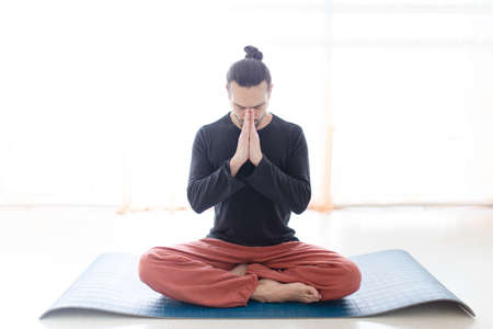 Young Caucasian long haired white man is performing yoga in a studio or house.の写真素材