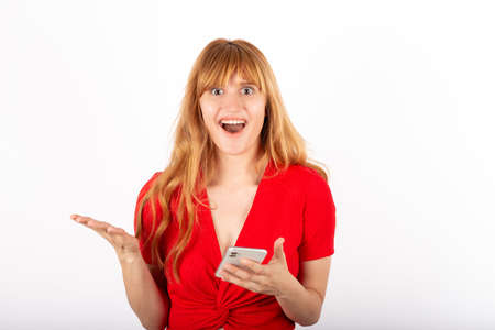 Cheerful portrait of young woman in studio. She is checking mobile phone.の写真素材