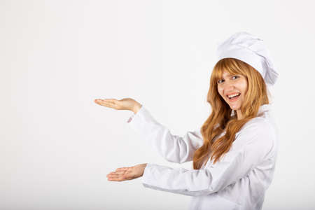 Beautiful smiling woman chef portrait in studio she services an empty spaceの写真素材