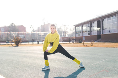 young beautiful caucasian woman doing stretching exercise on the sports groundの写真素材