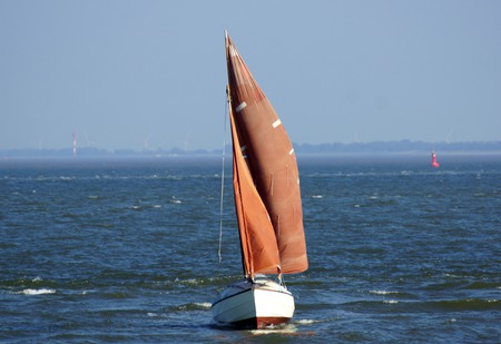 wind in red sail a small sailboat on the water