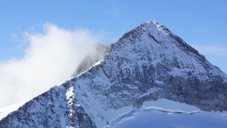 beautiful mountain with snow and a cloudの写真素材